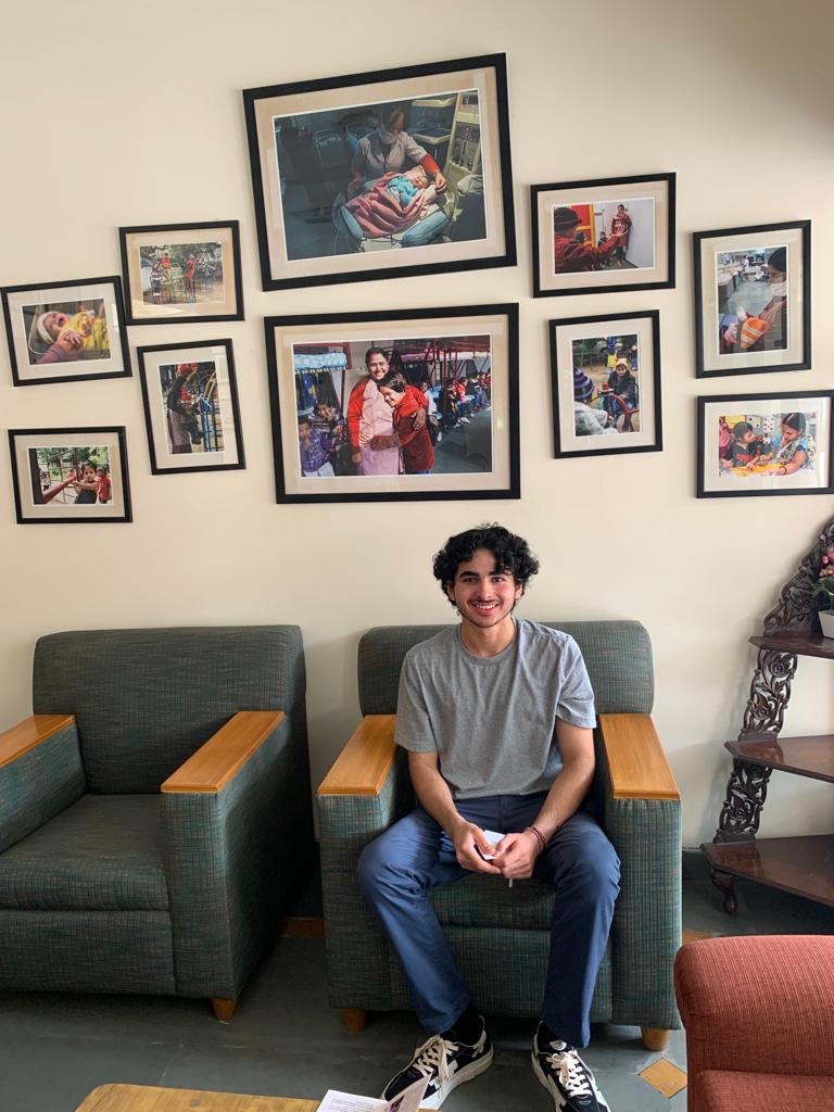 A volunteer sitting at Palna beneath framed photos